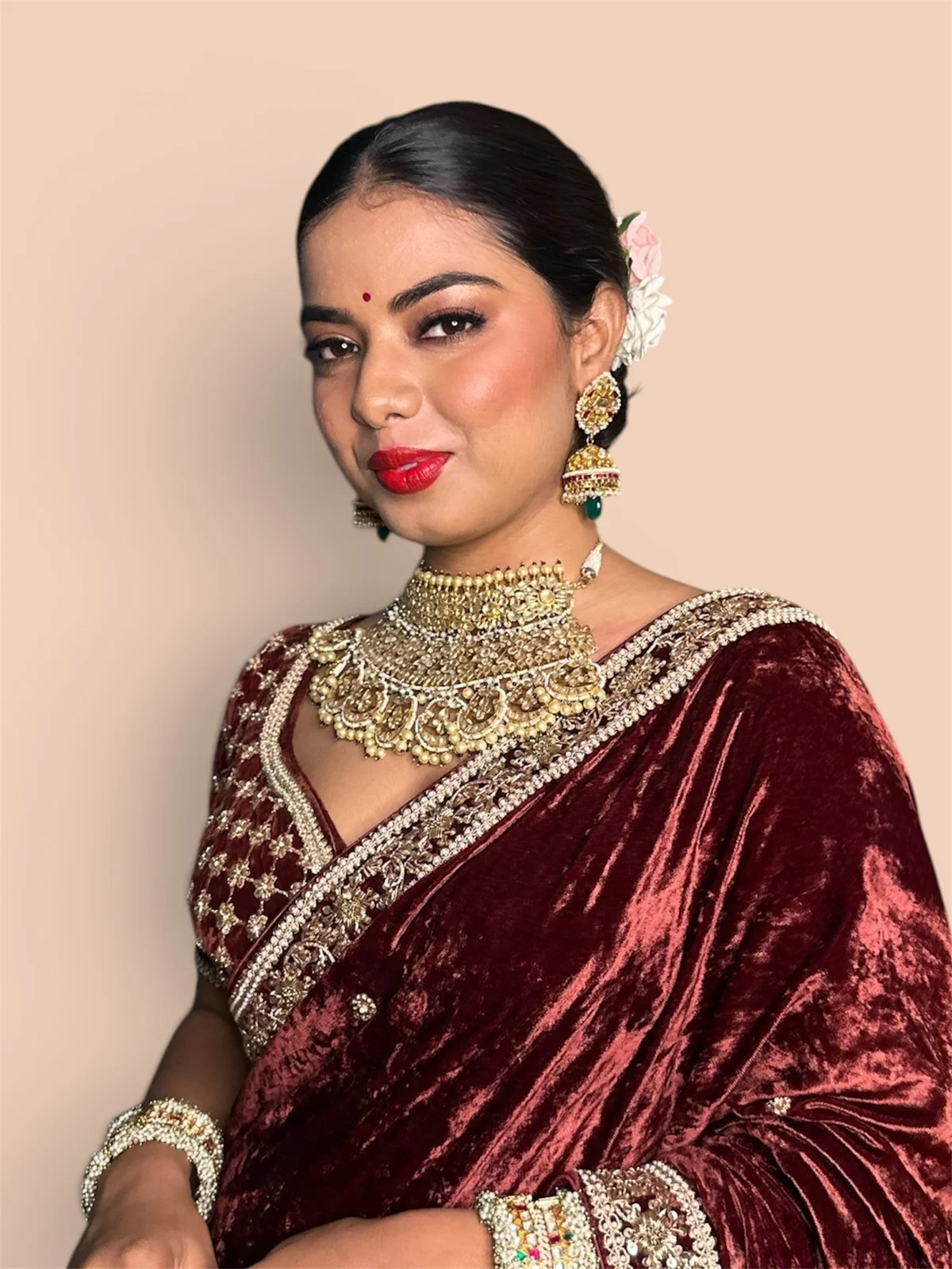 Bridal makeup by Pooja Arya: a red lip, softly sculpted eyes and polished hair with a burgundy sari and gold jewellery.